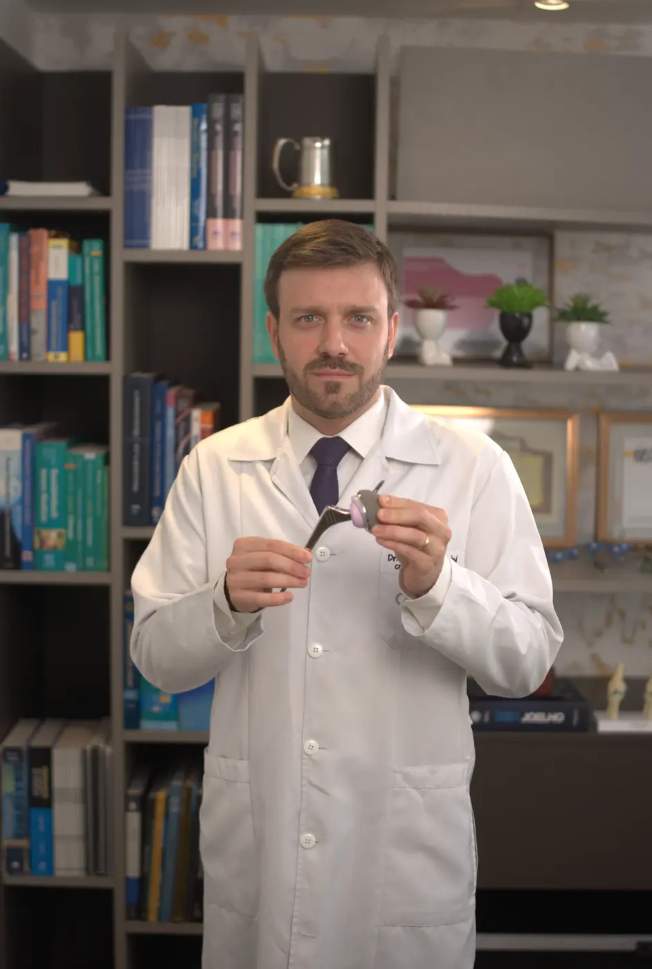 Dr. Gabriel Tomazini apresentando um modelo de prótese de quadril usada em cirurgias de artroplastia